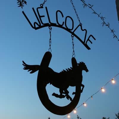 A silhouette of a horse under a "WELCOME" sign against a twilight sky.