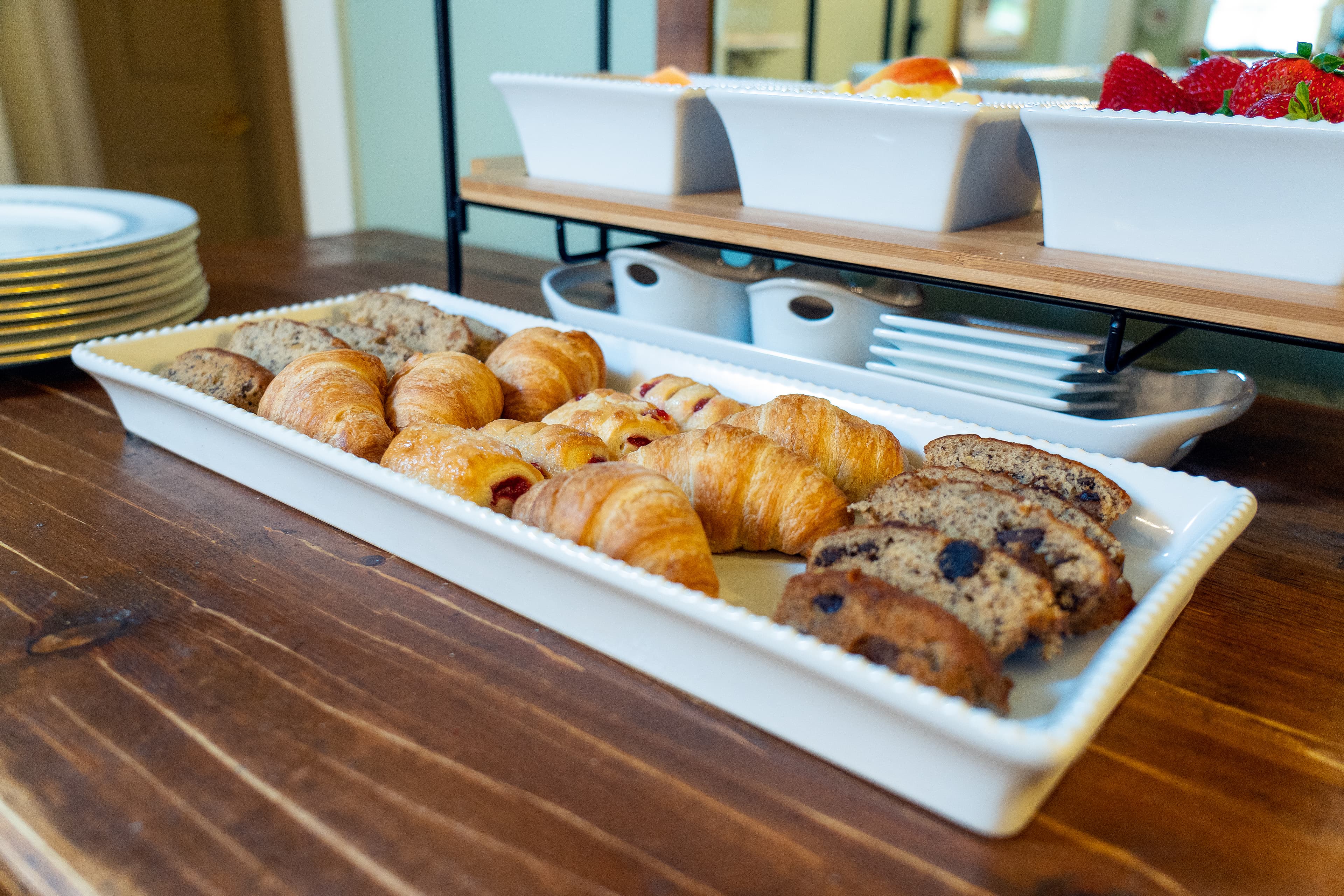 A platter of assorted pastries, including croissants and cookies, on a wooden table.