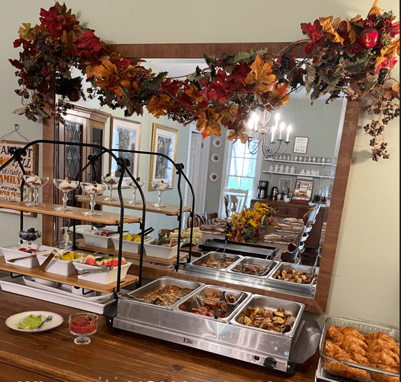 A buffet table with a variety of dishes, adorned with autumn decorations and reflected in a mirror.