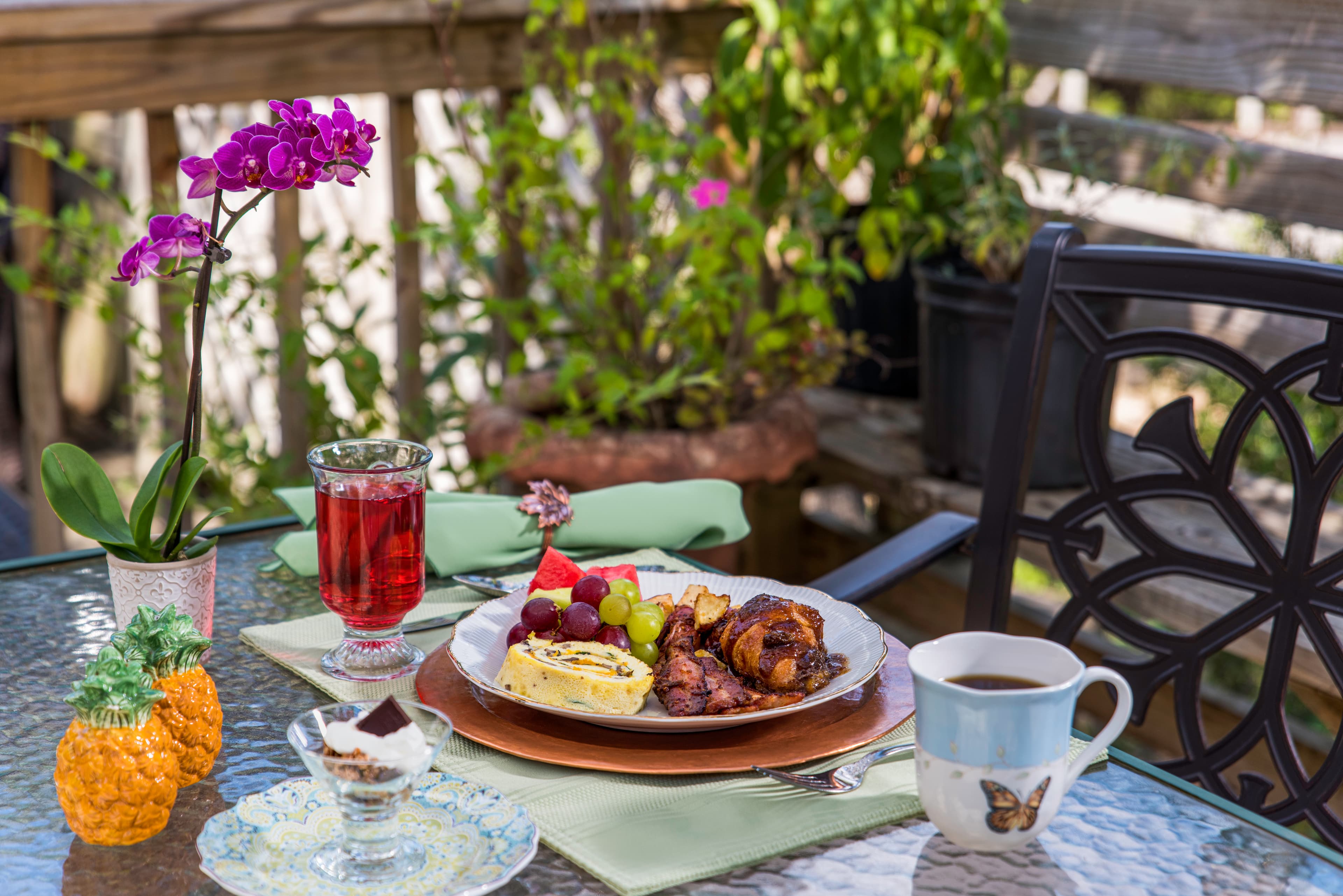 A beautifully arranged outdoor breakfast table featuring a plate of food, a drink, and decorative items.