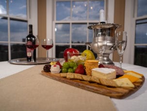 photo of a bottle of wine and a fruit and cheese plater